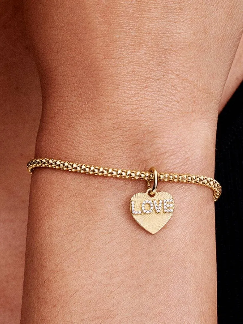 Close-up van de hart charm met de tekst 'LOVE' om een pols, zijaanzicht.