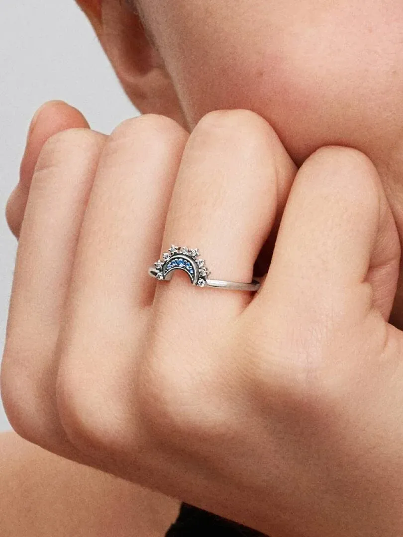 Close-up of the crescent moon ring with blue pavé worn on a finger, side view shot.