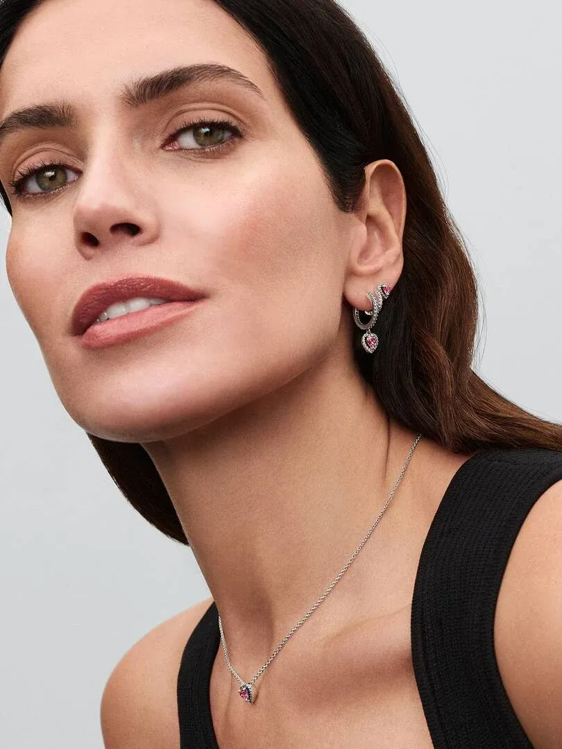 Gros plan d'un modèle portant un collier avec pendentif rose et boucles d'oreilles assorties, vue de profil.