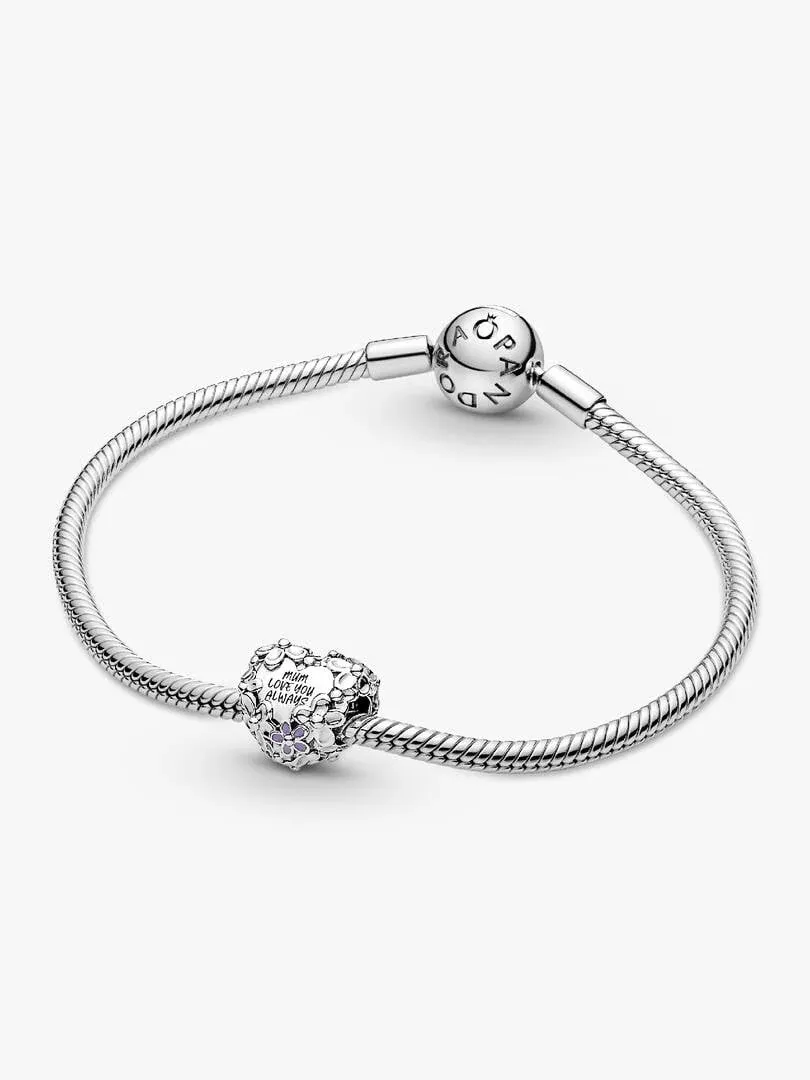 Charm de corazón con detalles florales sobre brazalete de plata, vista frontal en ángulo, fondo blanco.