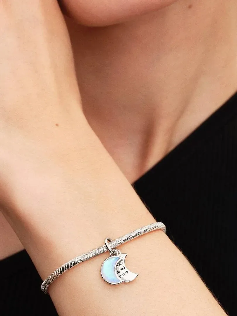Close-up van de armband met halve maan charm om een pols, wazige achtergrond met zwarte kleding.