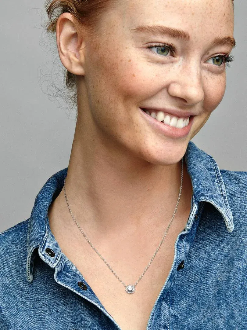 Gros plan du collier en argent sur le cou d'un mannequin portant une chemise en jean, vue de face.