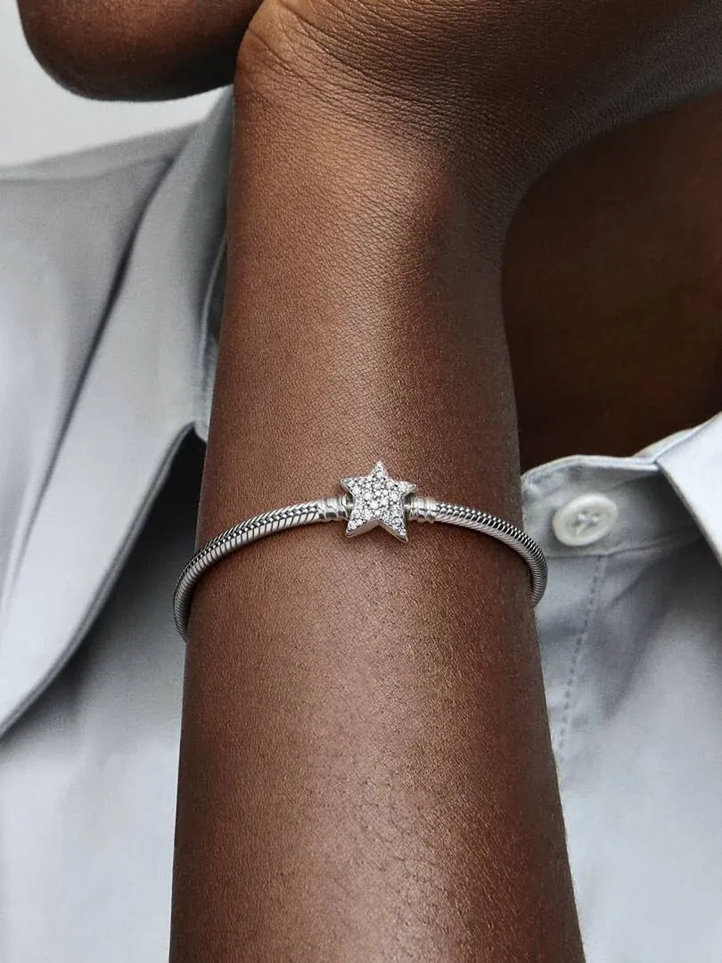 Close-up van de armband met ster sluiting om een pols, vooraanzicht tegen een lichte shirt achtergrond.