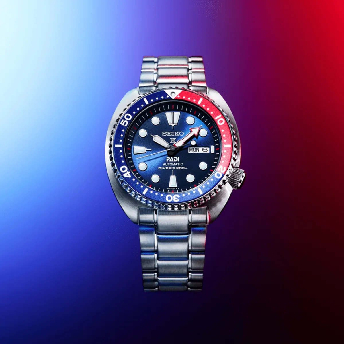 Vista frontal del reloj centrada sobre un fondo degradado en tonos azul y rojo.