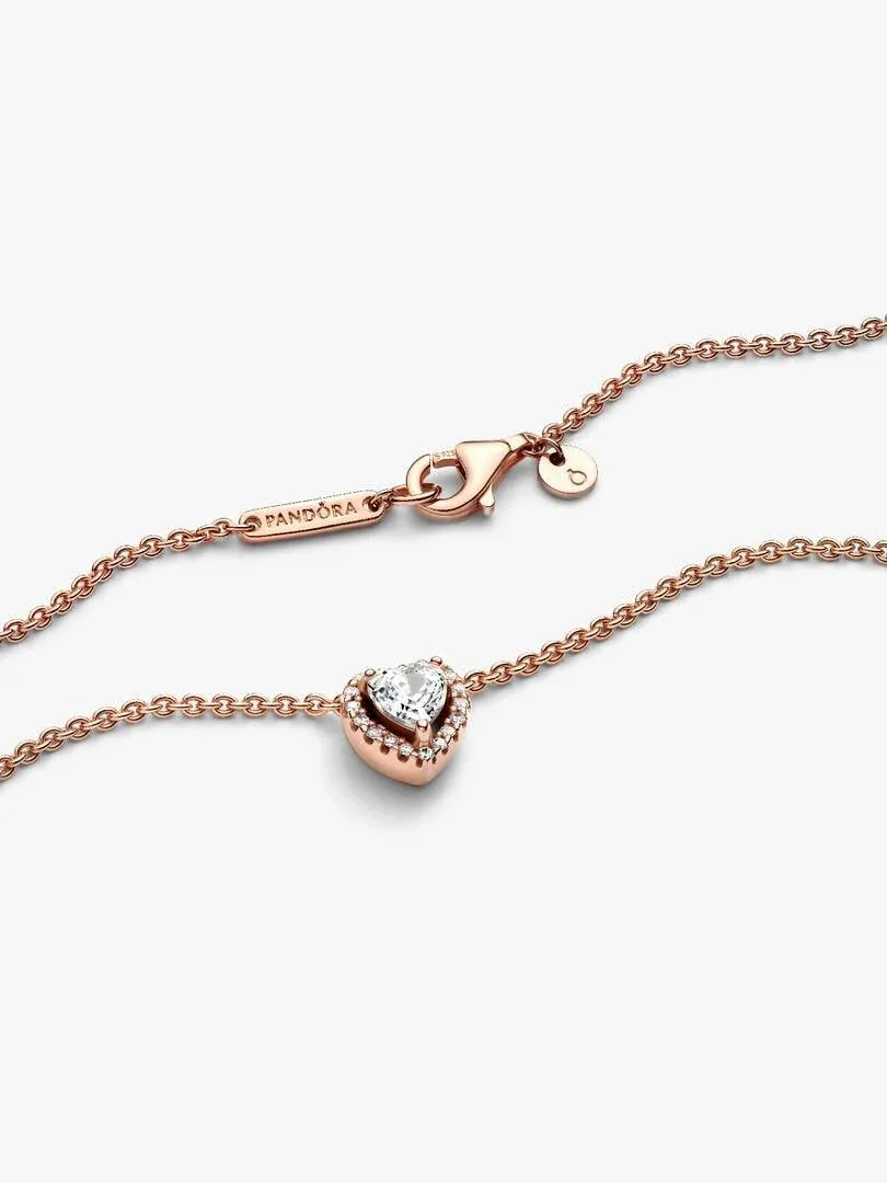 Gros plan du pendentif cœur et du fermoir logoté sur fond blanc.