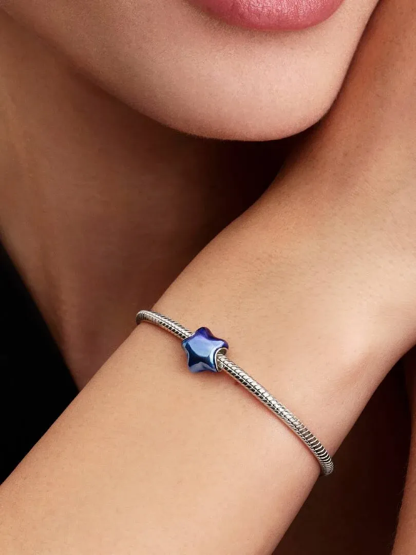 Gros plan du charm étoile bleue sur un bracelet, porté sur le poignet d'un modèle, vue de profil.
