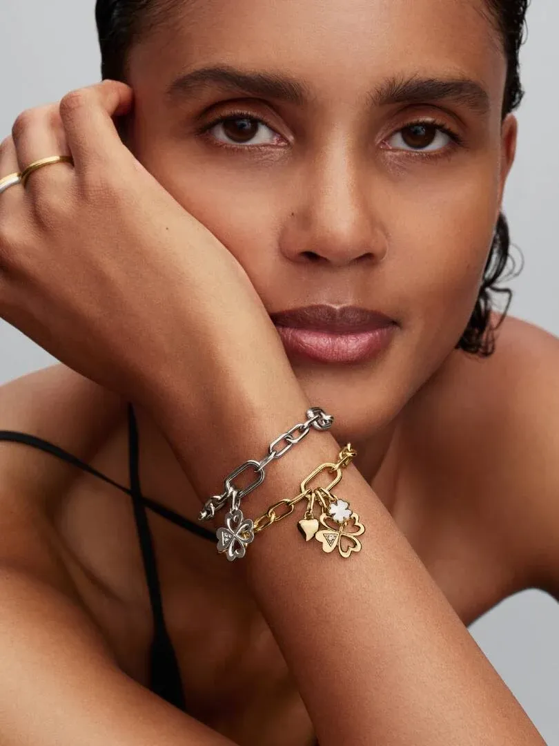 Close-up of a wrist wearing a link bracelet with charms, model posing against a neutral background.