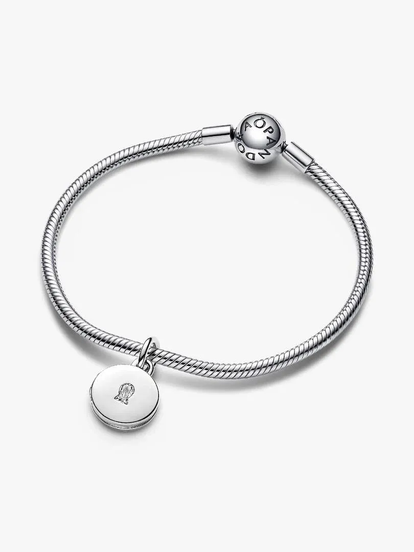Bracelet en argent avec charm circulaire gravé, vue de dessus sur fond blanc.