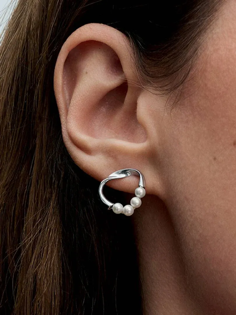 Gros plan latéral d'une boucle d'oreille en perles portée à l'oreille, fond de cheveux flou.