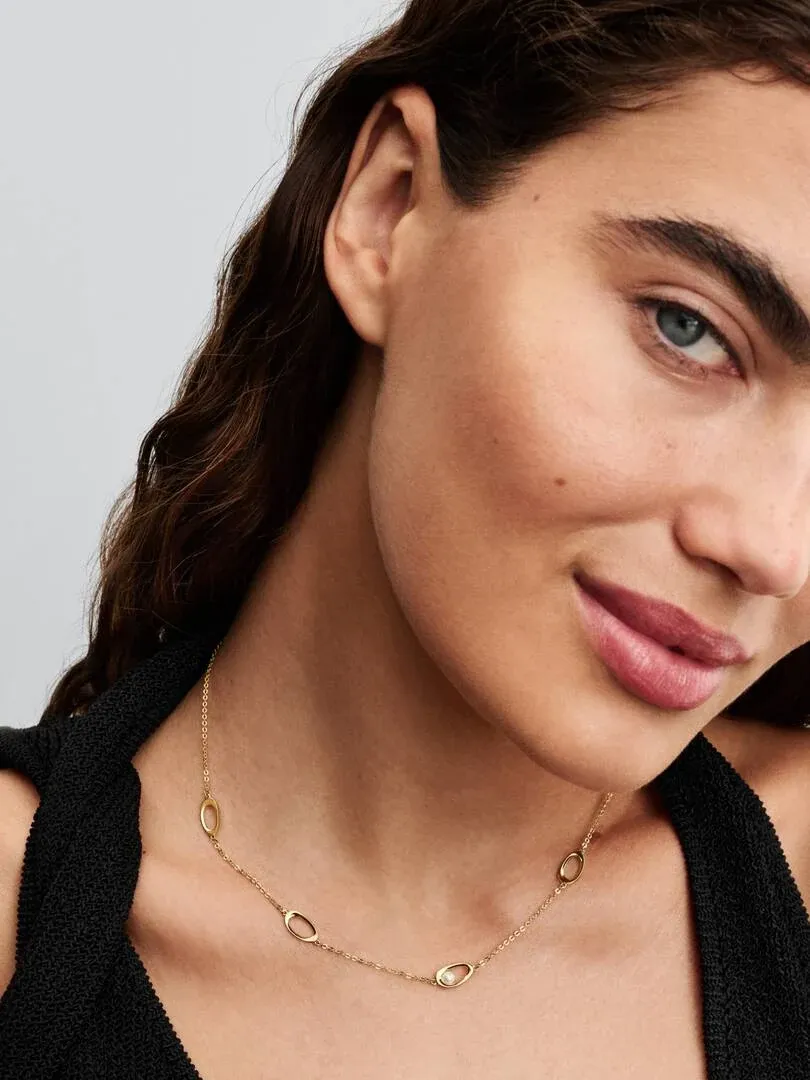 Gros plan du collier avec perle sur le cou d'un mannequin, vue de profil sur fond neutre.