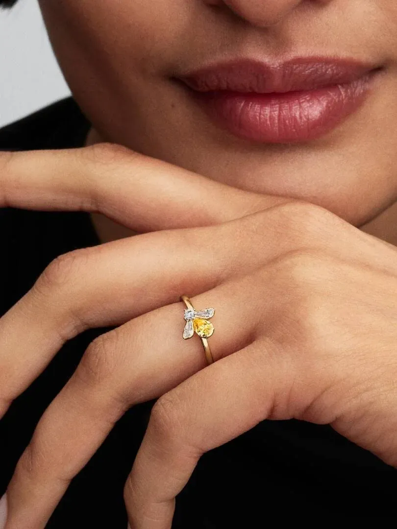 Primer plano del anillo de abeja en el dedo anular, toma lateral con fondo desenfocado.