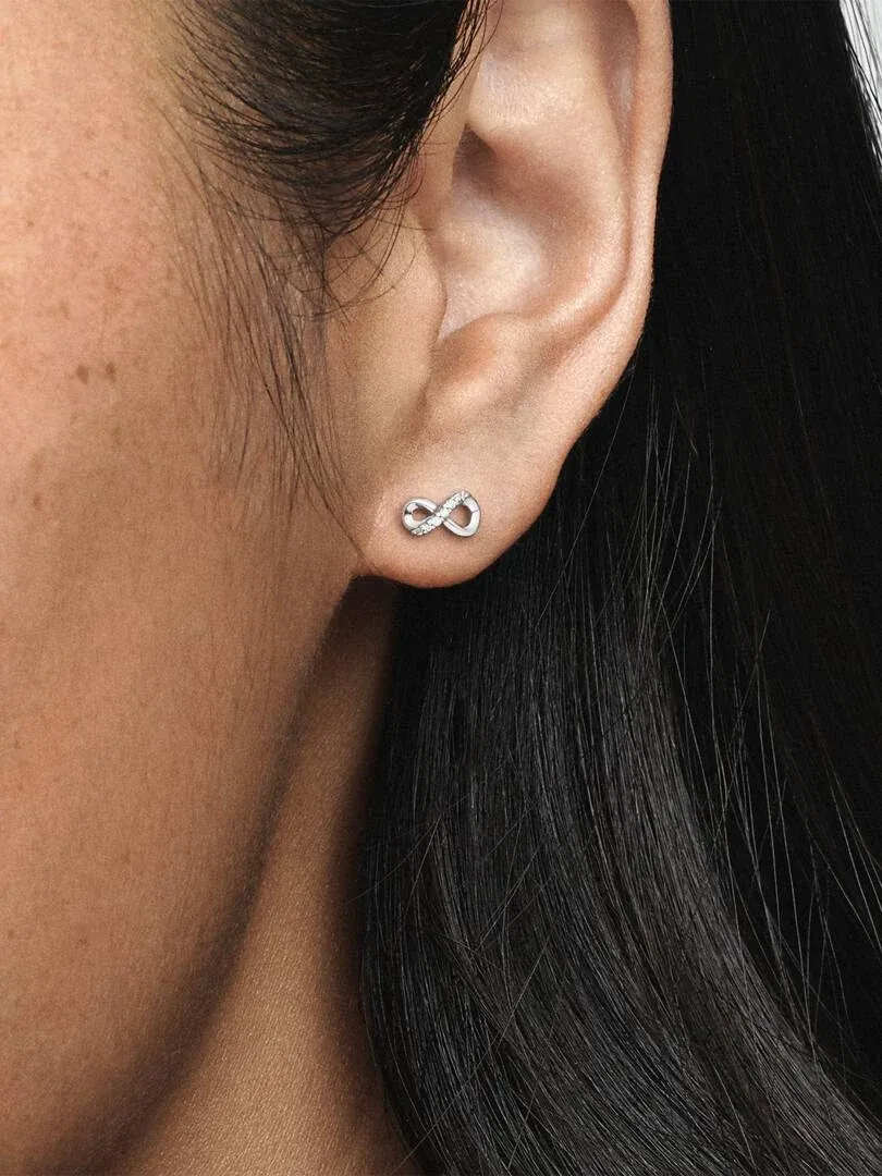 Zijaanzicht close-up van een infinity-vormige oorstuds gedragen aan een oorlel.