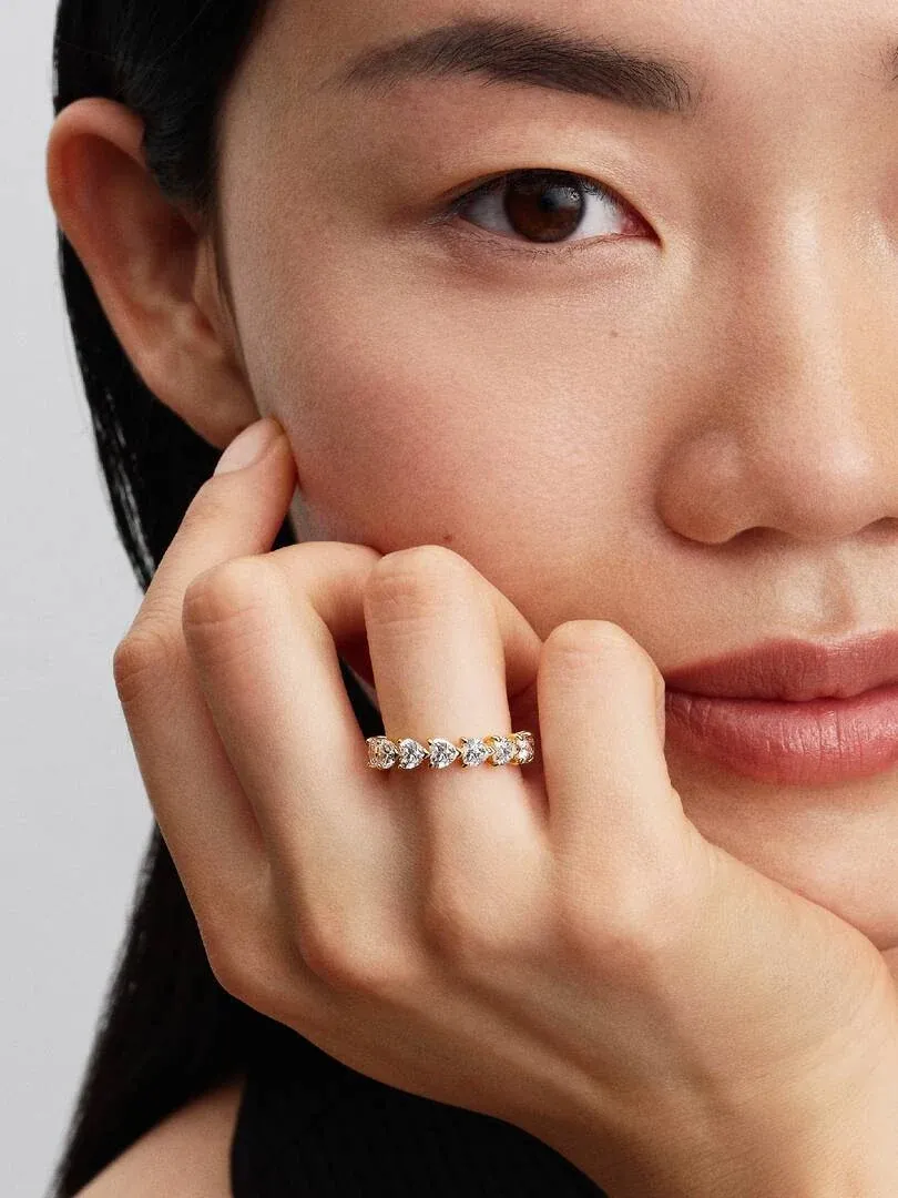 Primer plano del anillo de corazones puesto en el dedo, apoyado sobre la mejilla de una modelo.