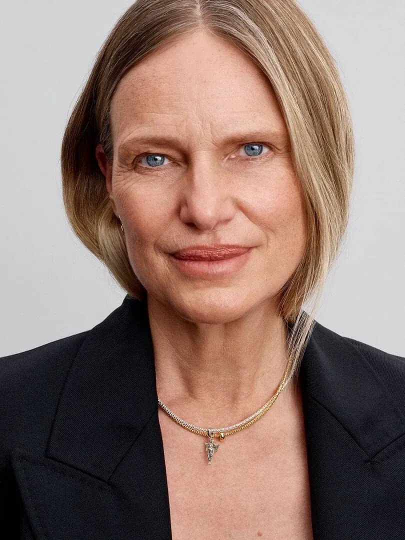 Primer plano de mujer con collar de Cupido, toma frontal sobre fondo gris neutro.