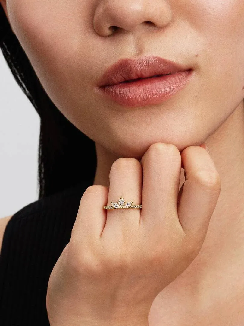 Primer plano del anillo floral en el dedo anular, toma lateral con modelo y fondo neutro.