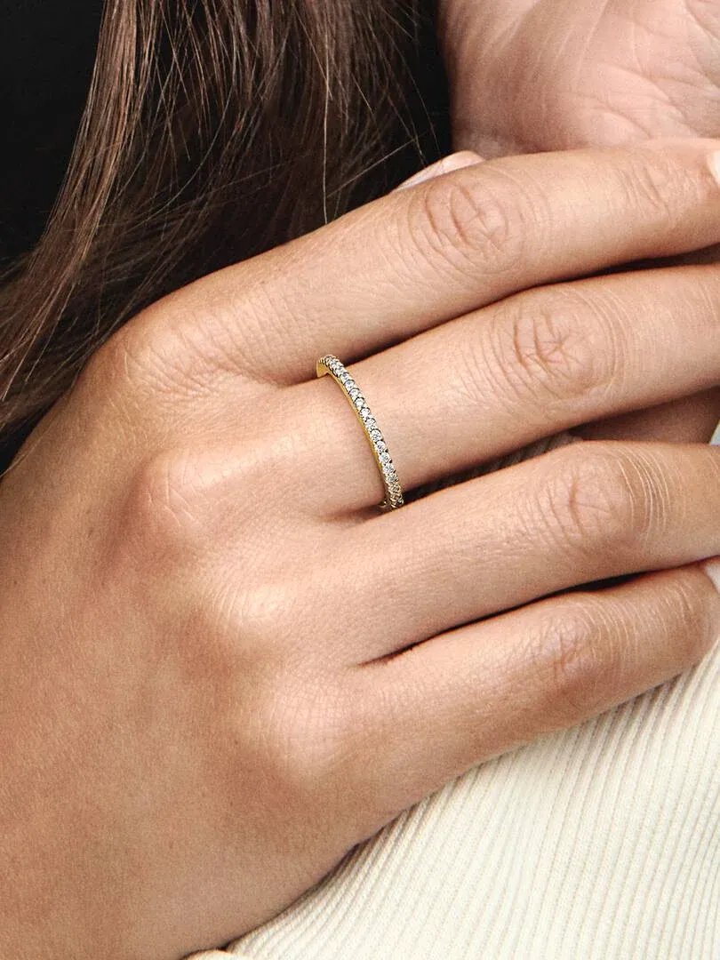 Primer plano del anillo con circonitas puesto en el dedo, toma lateral sobre fondo de ropa clara.