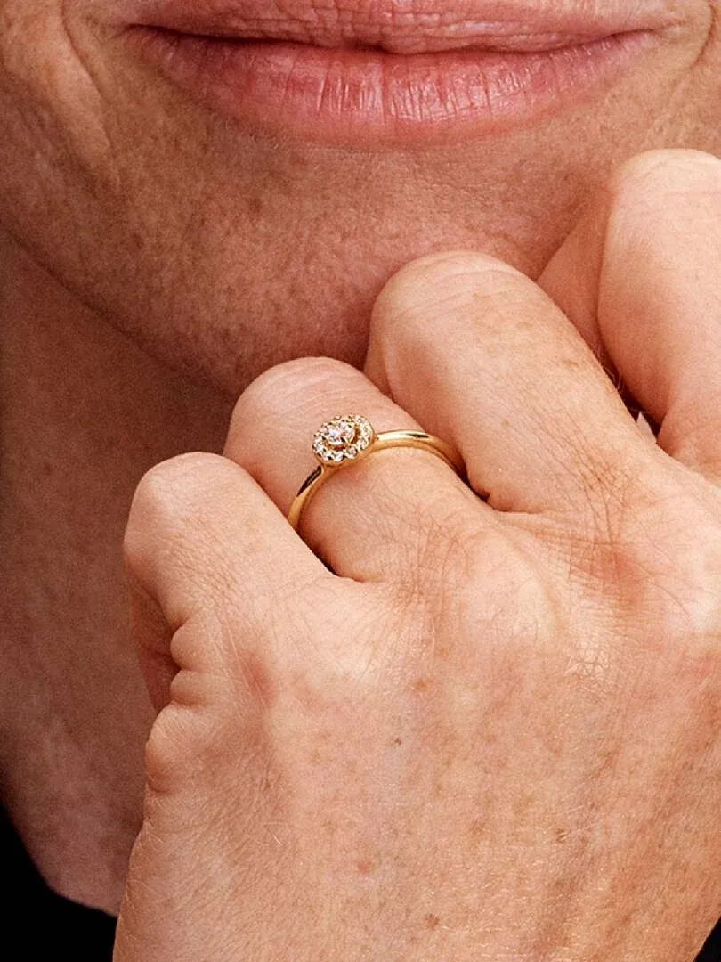 Primer plano del anillo con circonita central puesto en el dedo, toma lateral junto al rostro.