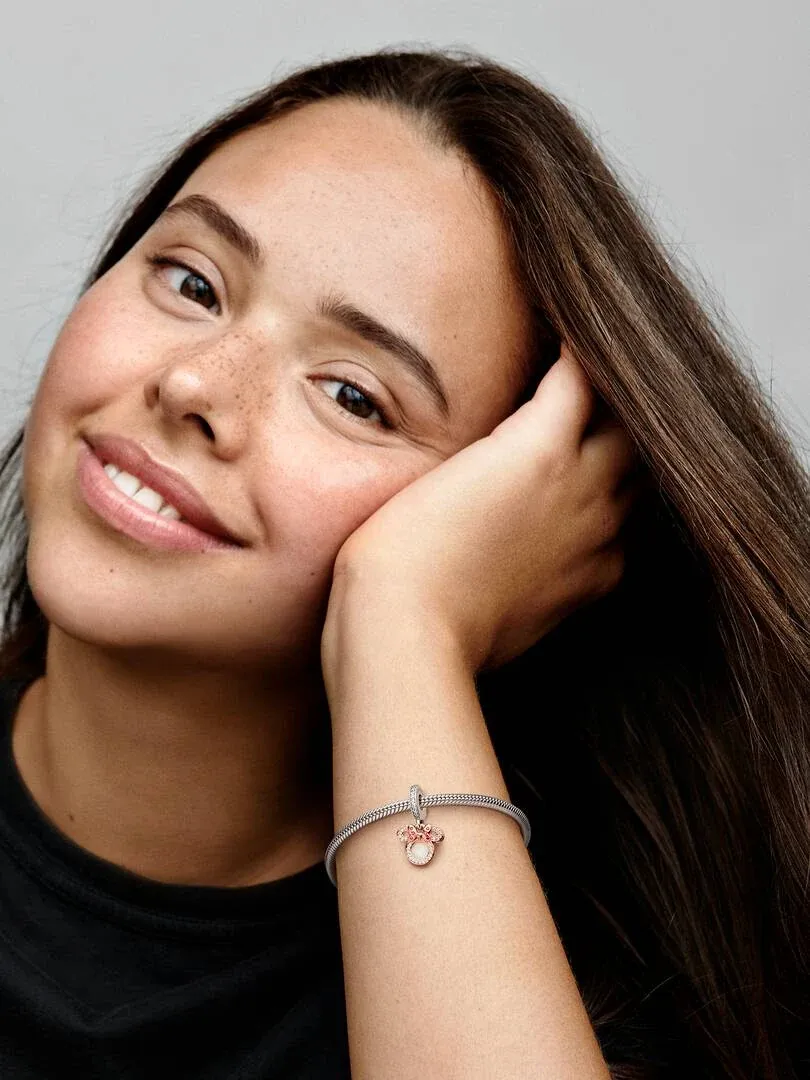 Close-up of the Minnie Mouse charm on a bracelet worn on a model's wrist against a neutral background.