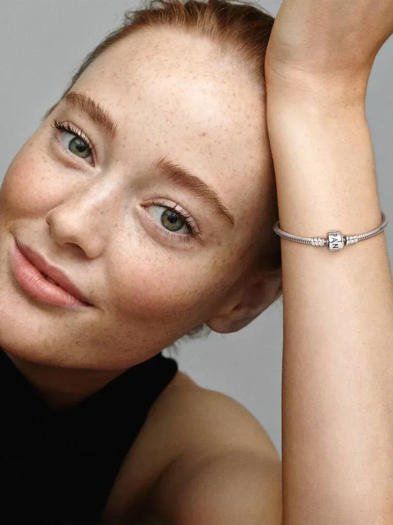 Close-up van een slangkettingarmband om de pols, zijaanzicht met model tegen een neutrale achtergrond.