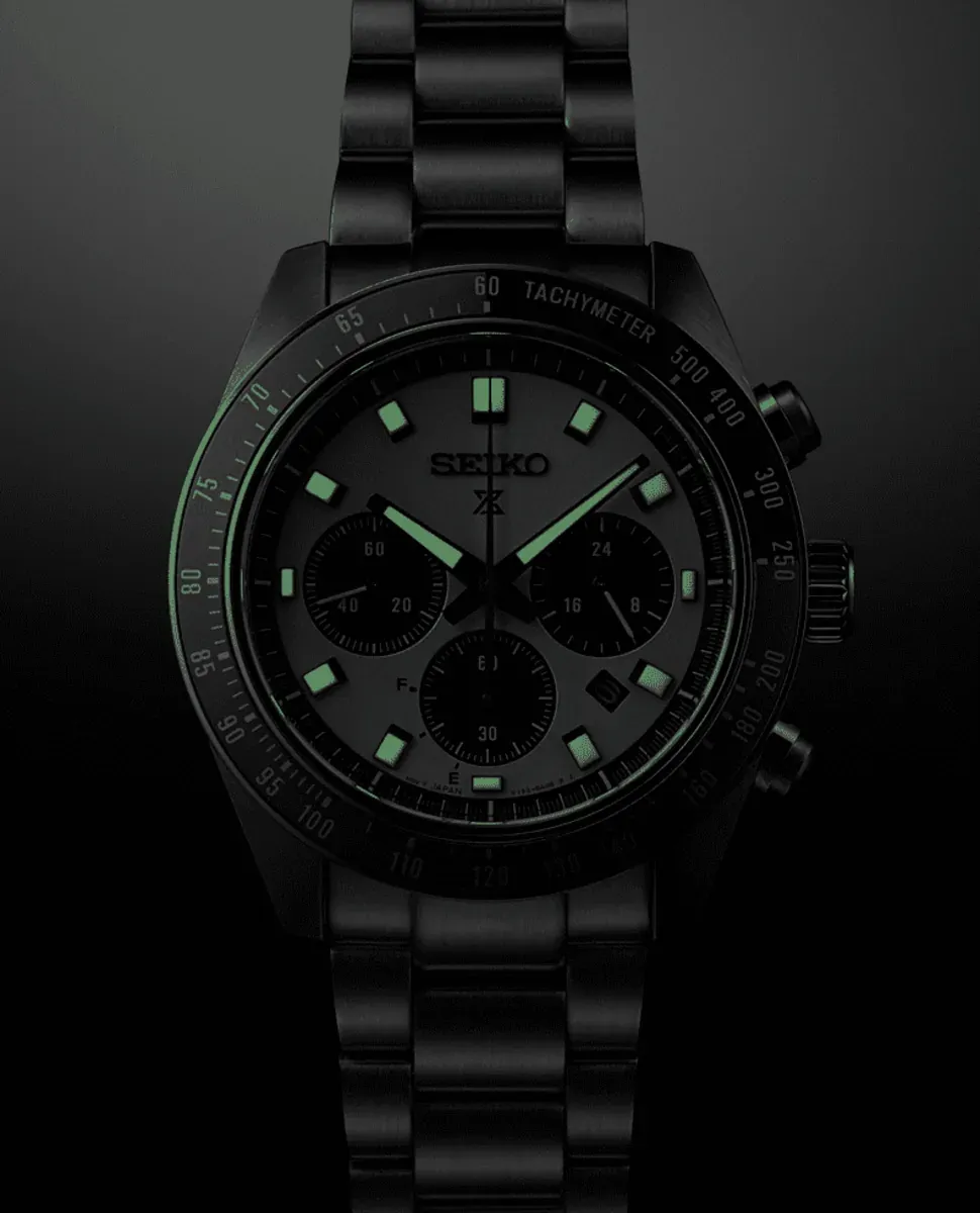 Vista frontal del reloj en oscuridad sobre fondo negro, destacando la luminiscencia verde de índices y manecillas