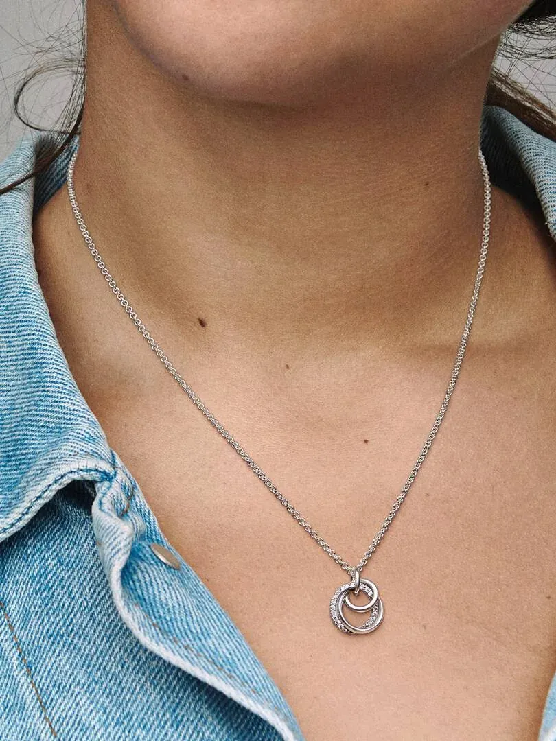 Close-up of the three interlocking ring pendant necklace worn on a neck with a denim jacket.