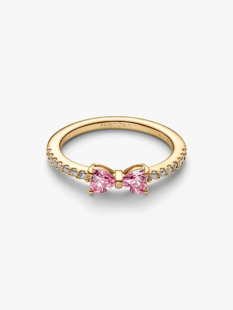 Anillo de lazo rosa visto en ángulo lateral, banda con pavé de circonitas y fondo blanco.