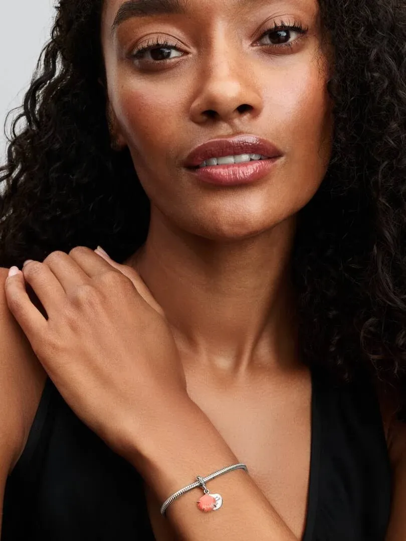 Close-up van pols met armband en koraal schelpen charm, op model met neutrale achtergrond.