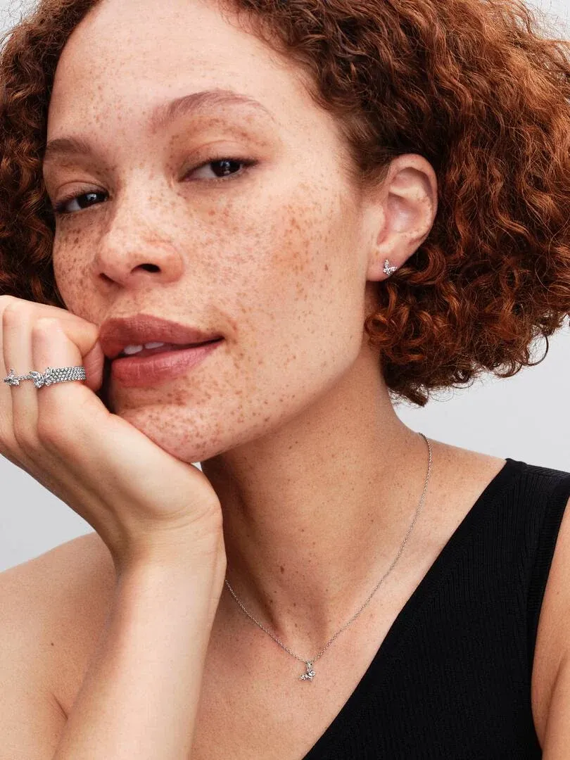 Gros plan d'un modèle portant le collier papillon et la bague assortie, vue de face sur fond neutre.