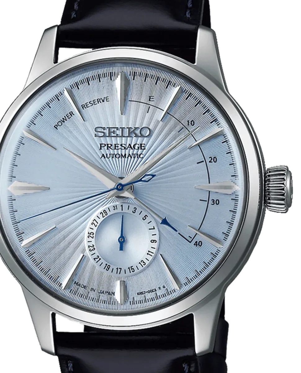 Primer plano de la esfera azul con acabado radial, fondo blanco, detalle del dial de fecha y reserva de marcha.