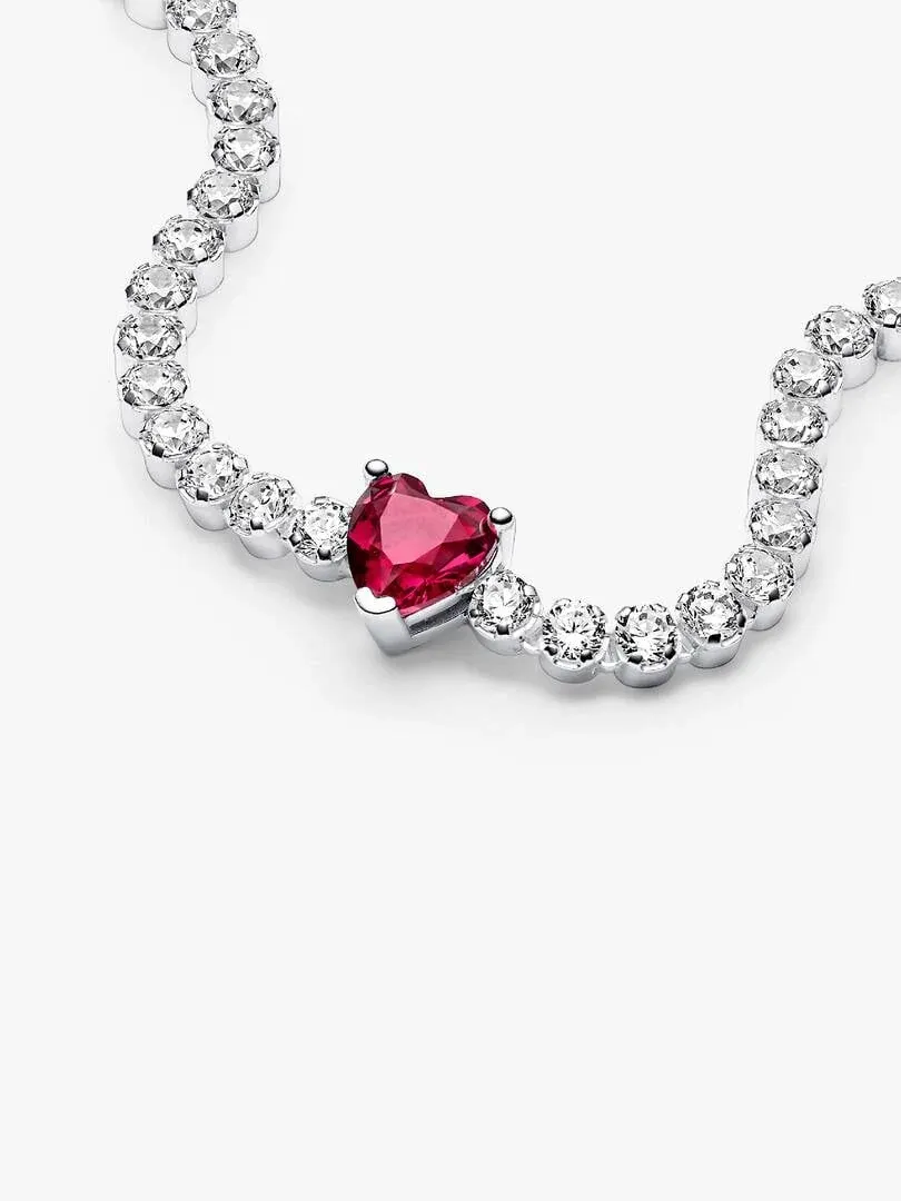 Close-up of the red heart-shaped gem and pavé cubic zirconia stones, white background.