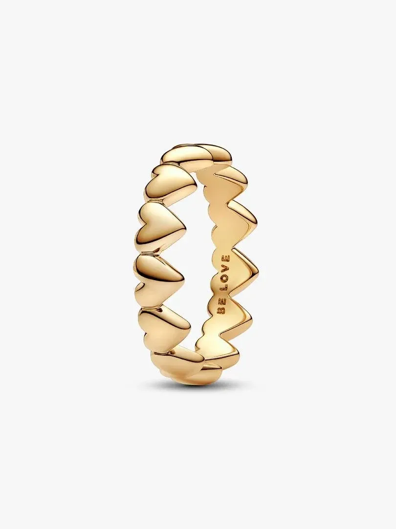 Anillo de corazones visto en ángulo lateral, fondo blanco, detalle del grabado 'BE LOVE' en el interior.