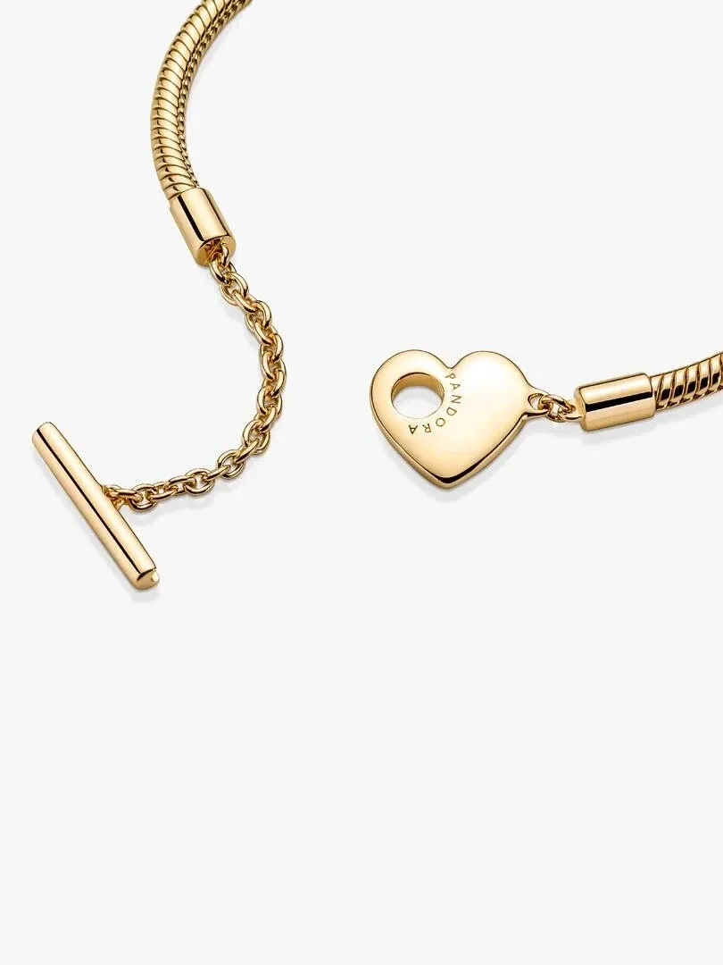 Primer plano de la pulsera con cierre de barra en T y dije de corazón, sobre fondo blanco.