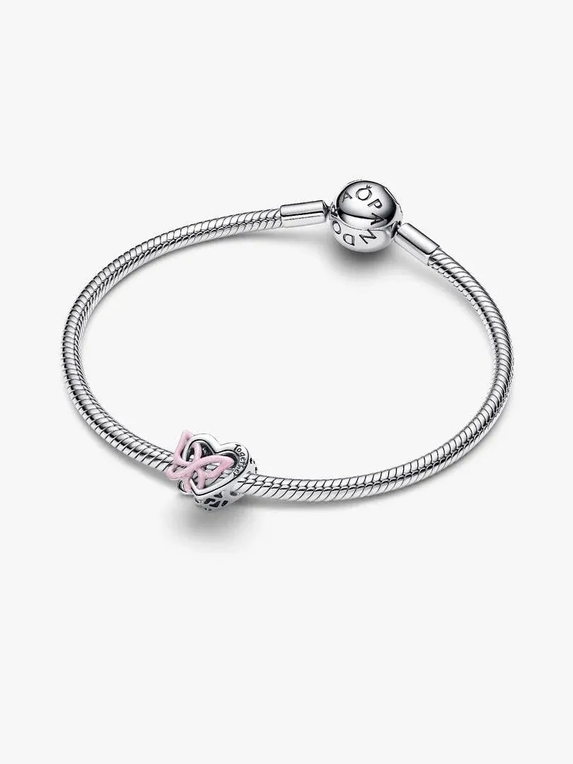 Pulsera de plata con charm de corazón y mariposa rosa, vista frontal en ángulo sobre fondo blanco.