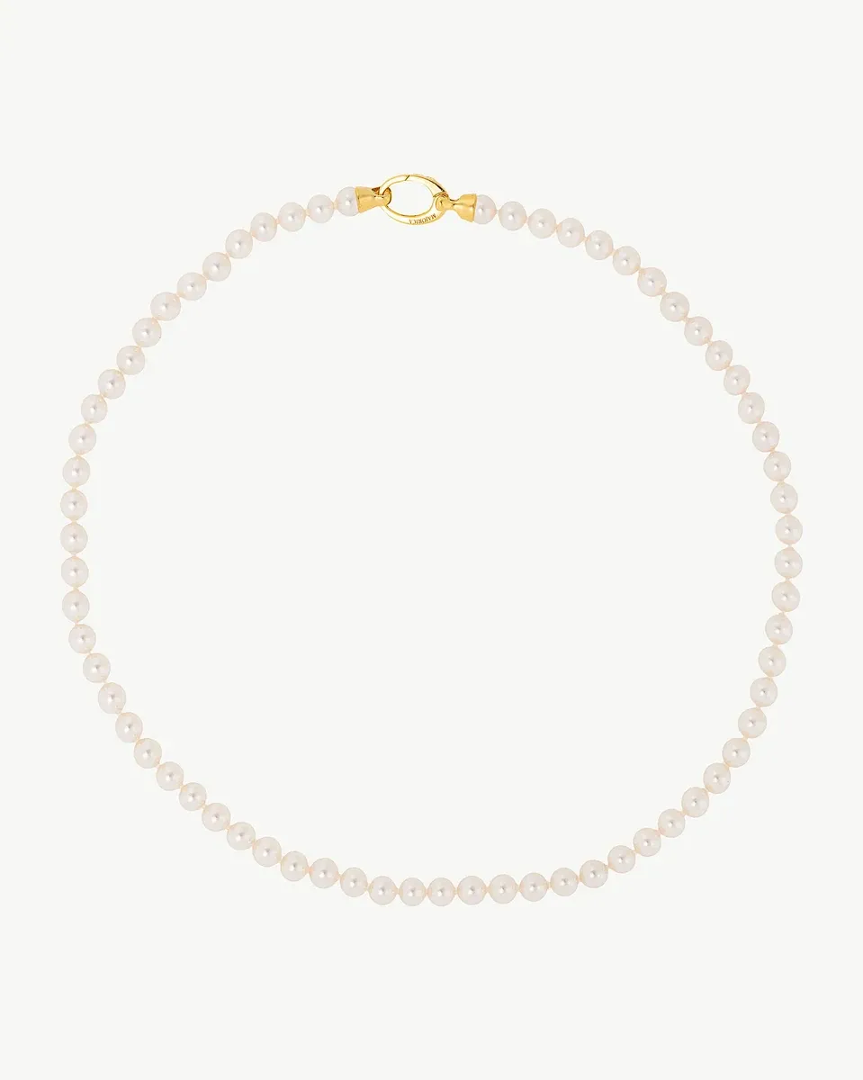 Collier de perles disposé en cercle sur fond blanc, vue de face avec fermoir doré visible.