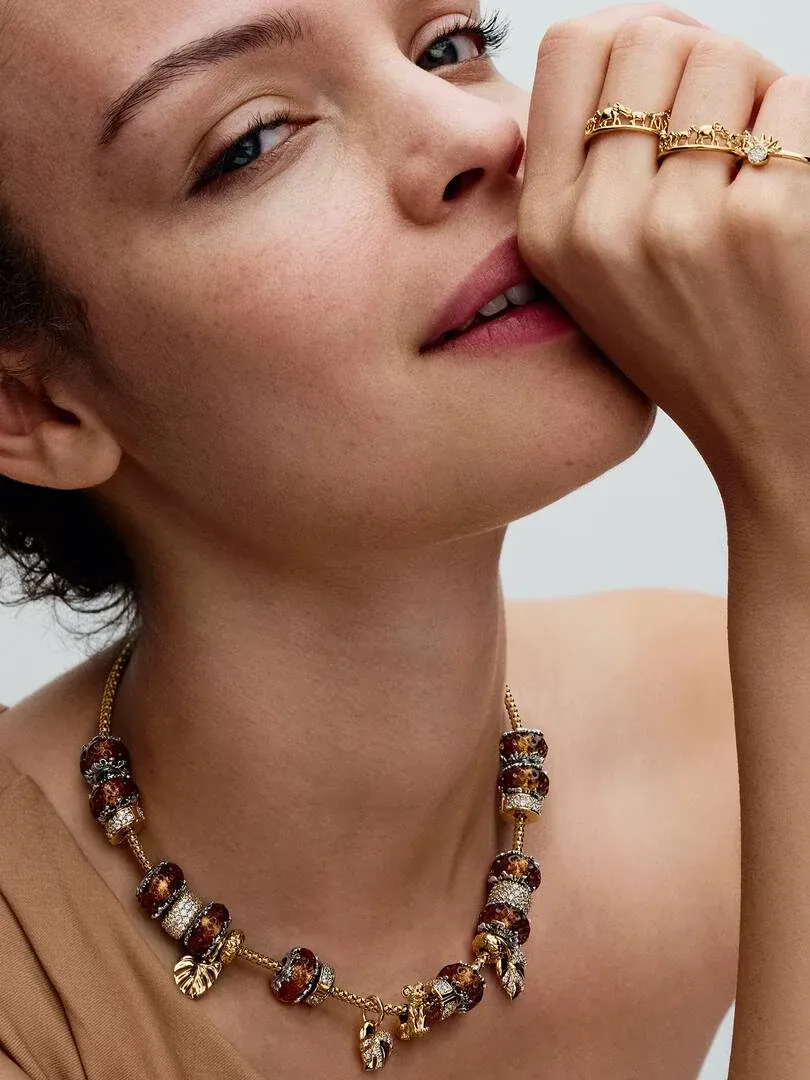 Gros plan d'un modèle portant un collier et des bagues dorés, vue de profil.