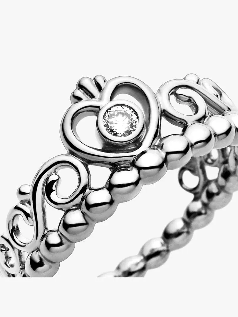 Primer plano de perfil del anillo con circonita central, fondo blanco, detalle del diseño de cuentas y filigrana.