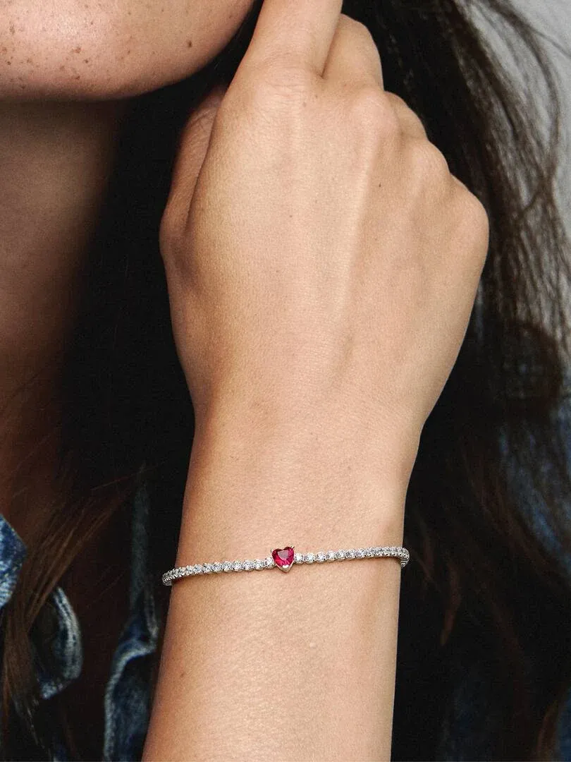 Close-up of the red gem bracelet on a wrist, side view with blurred background.
