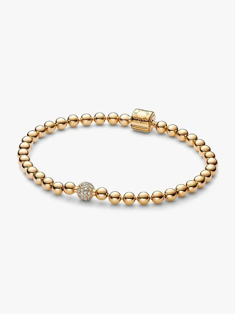 Pulsera de cuentas doradas vista desde arriba, fondo blanco, detalle del cierre de barril y cuenta con pavé.