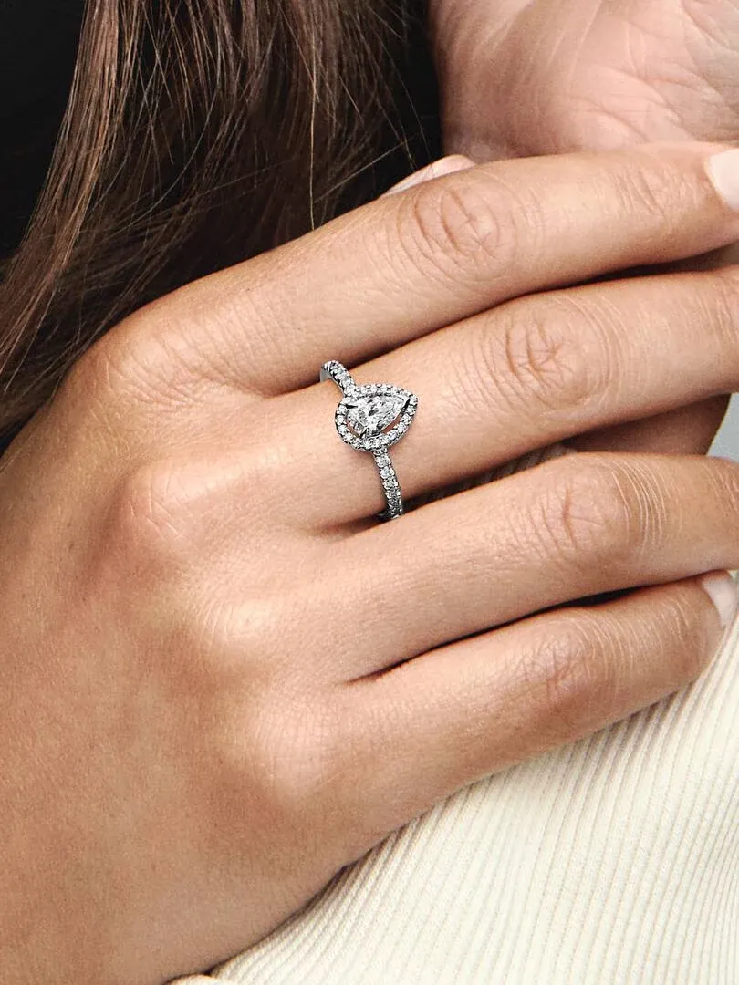 Close-up van de peervormige ring gedragen aan een vinger, zijaanzicht tegen een wazige achtergrond.