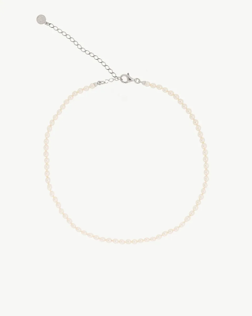 Pearl necklace arranged in a circle on a white background, front view showing clasp and extender chain.