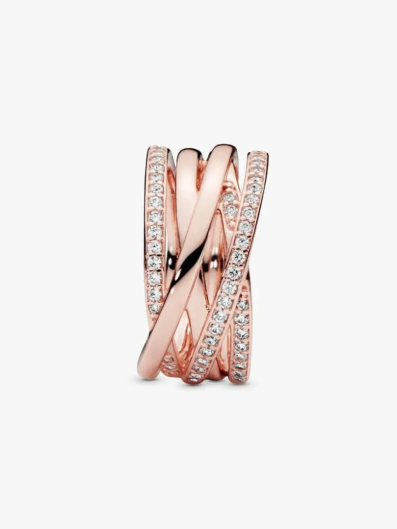 Anillo entrelazado en oro rosa con circonitas, vista frontal ligeramente lateral sobre fondo blanco.