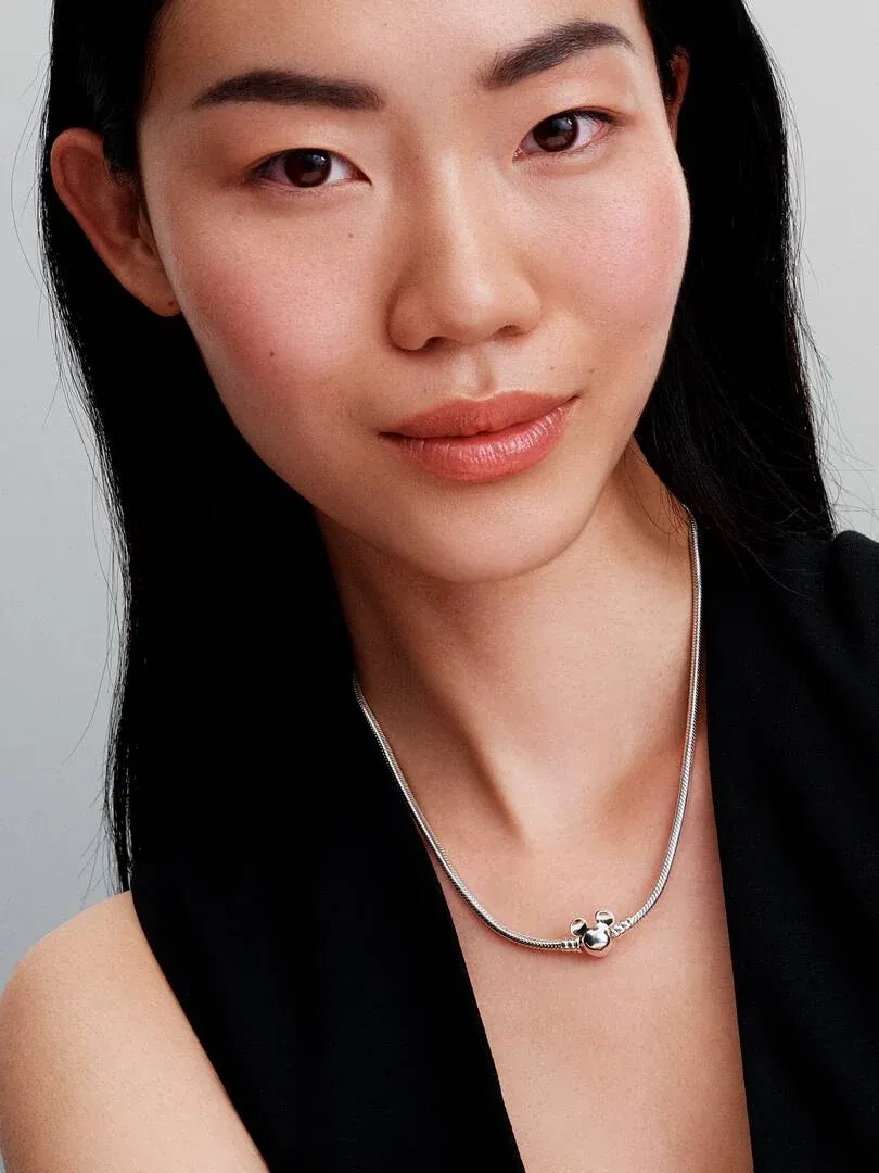 Nahaufnahme der Schlangenkette mit Mickey-Mouse-Verschluss am Hals eines Models.