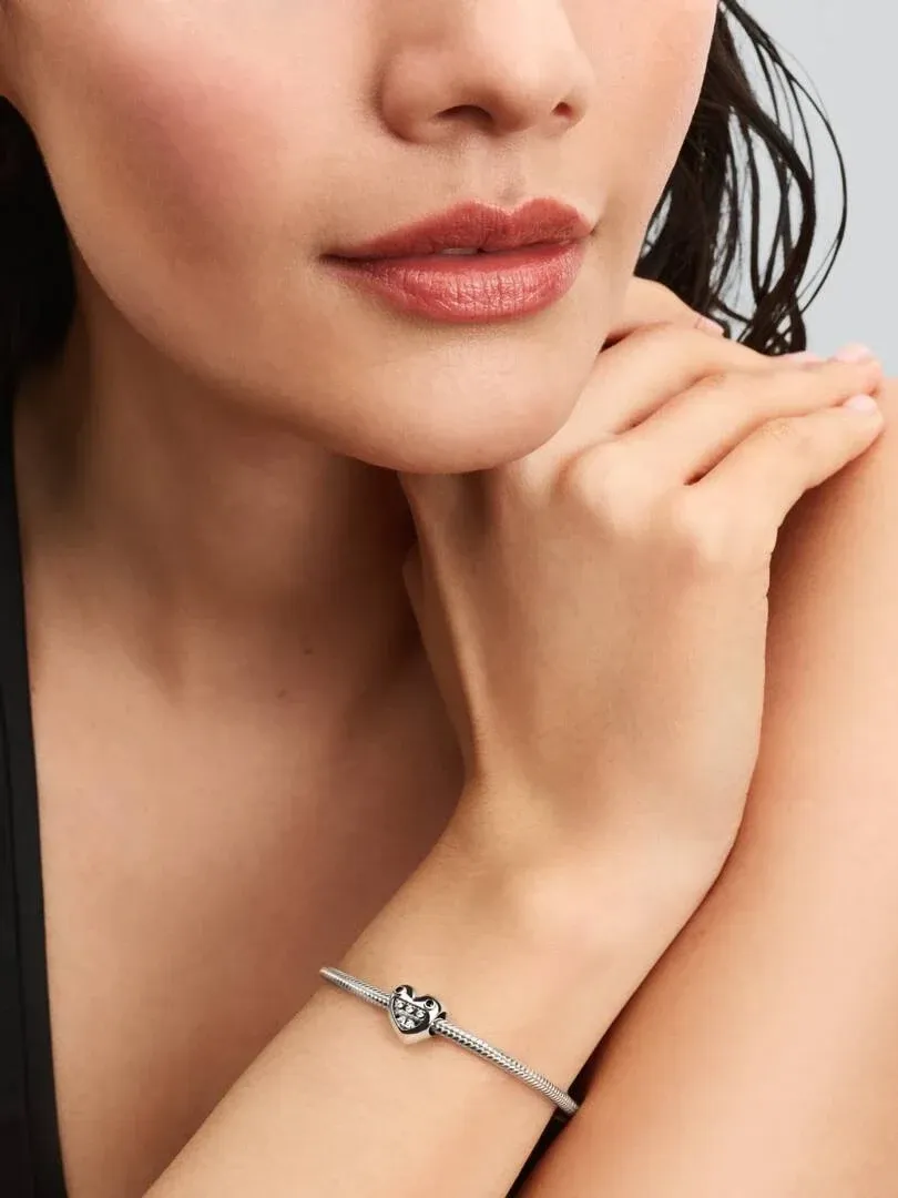 Primer plano de la muñeca con el charm de corazón en una pulsera, toma lateral sobre modelo.