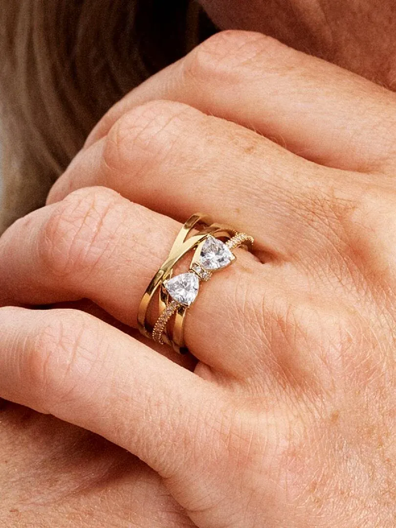 Primer plano del anillo de bandas cruzadas con circonitas puesto en el dedo, toma lateral sobre la mano.