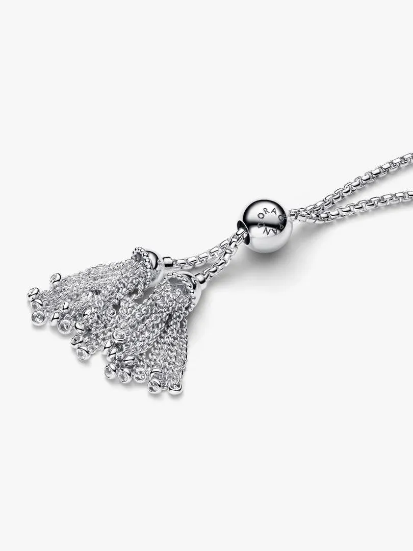 Primer plano del cierre de la pulsera con detalle de flecos y esfera grabada, fondo blanco.