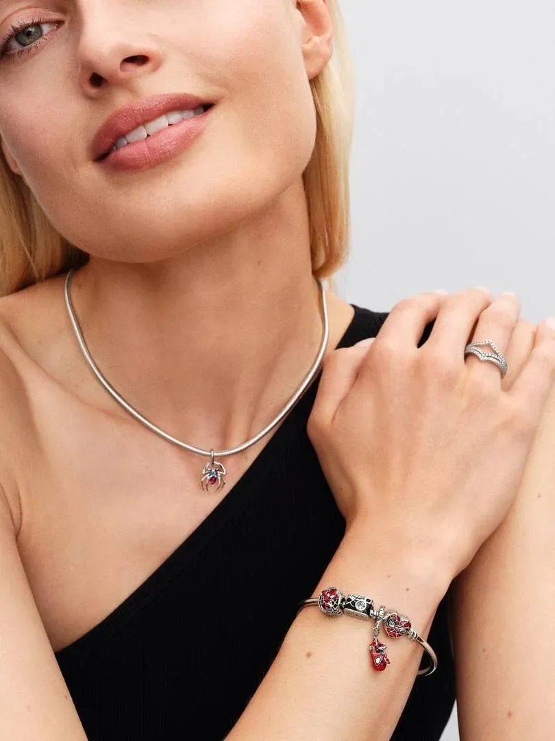 Modelo con collar de plata y pulsera con charms, toma de plano medio sobre fondo neutro.