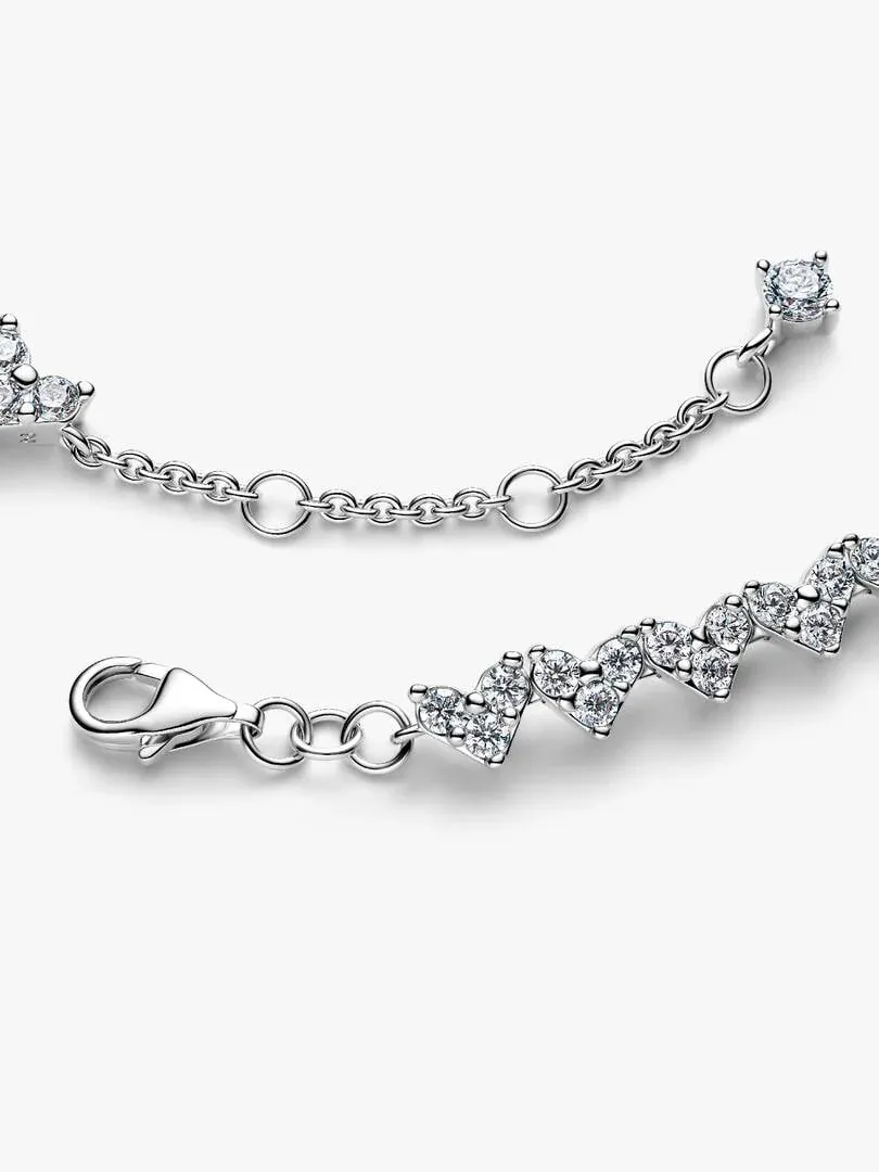 Gros plan du bracelet en argent avec motifs de cœurs et zircons, fond blanc.