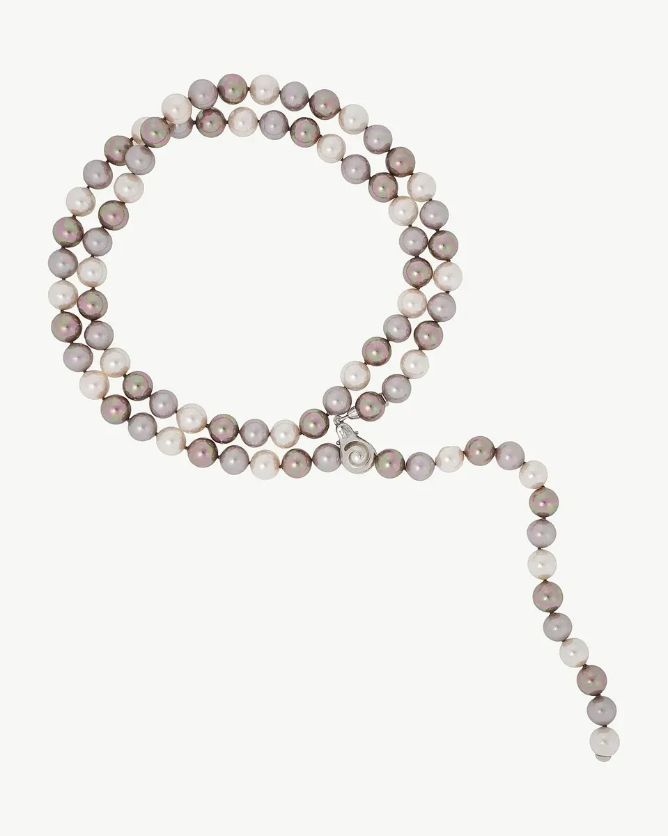 Collar de perlas dispuesto en forma circular sobre fondo blanco, vista cenital con caída lateral.