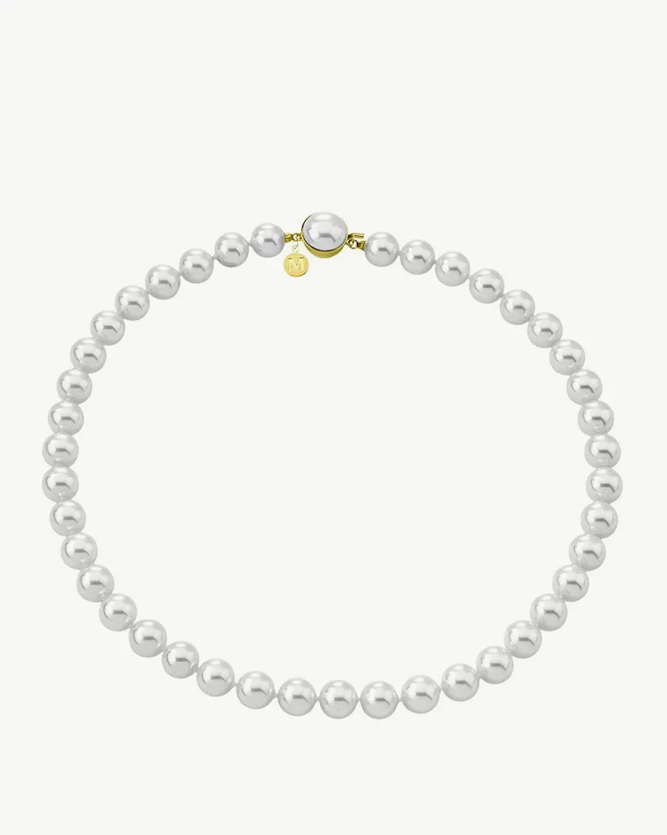 Collier de perles disposé en cercle sur fond blanc, vue de face avec détail du fermoir doré.