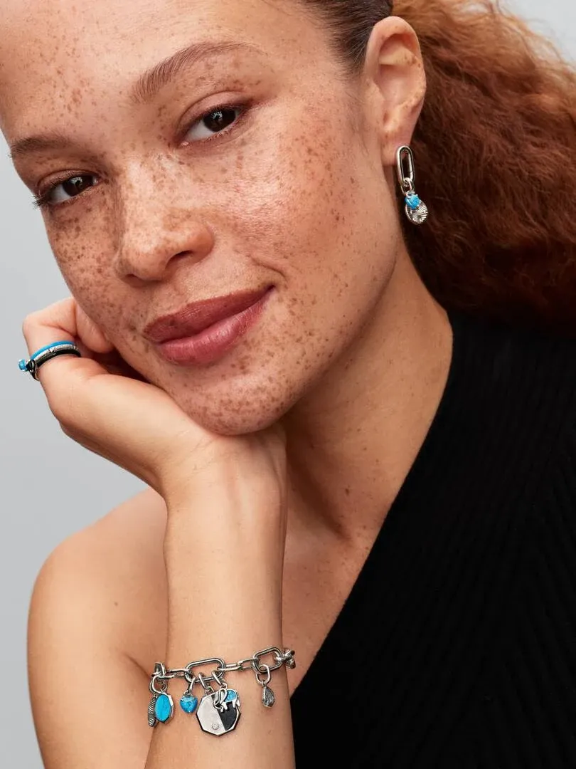 Close-up van model met oorknopjes en schakelarmband, onscherpe neutrale achtergrond.